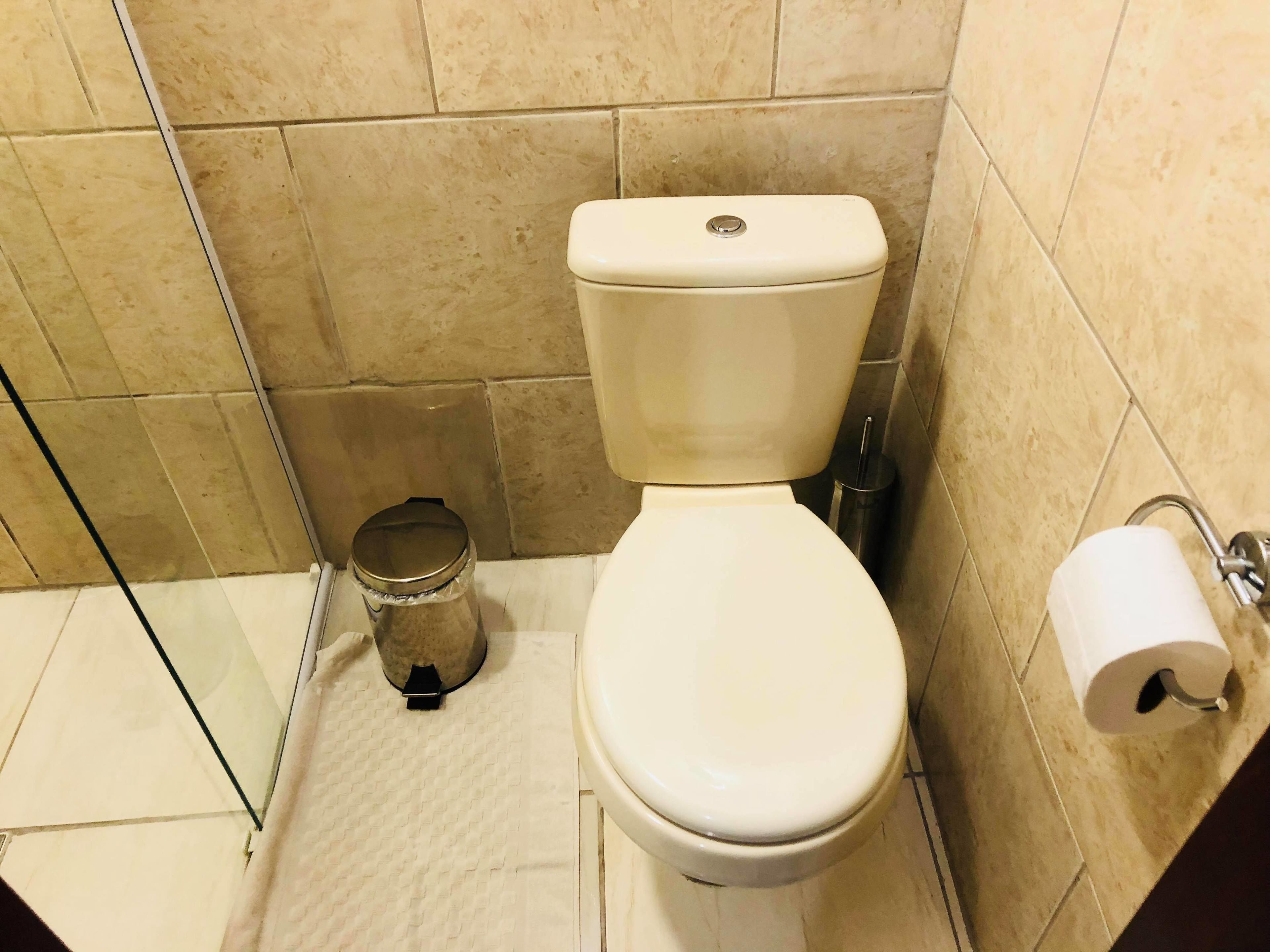 Ein kleines, sauberes Badezimmer mit Toilette, Mülleimer und Toilettenpapierhalter.