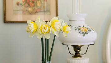 Un jarrón con narcisos y una lámpara blanca decorada con motivos florales.