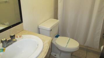 Un baño con lavamanos, inodoro y cortina de ducha.