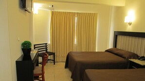 A hotel room with two beds, a desk, a chair, a television, and a window with curtains. - Hotel San Francisco (Culiacan)