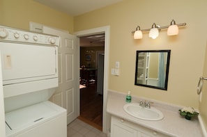 A compact bathroom with a white sink, a mirror, and a wall-mounted light fixture. - Beach House Comfort (Cocagne)