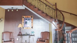 A grand staircase with ornate railings, a chandelier, and a polished wooden floor. - Black Gold Inn (Yoakum)