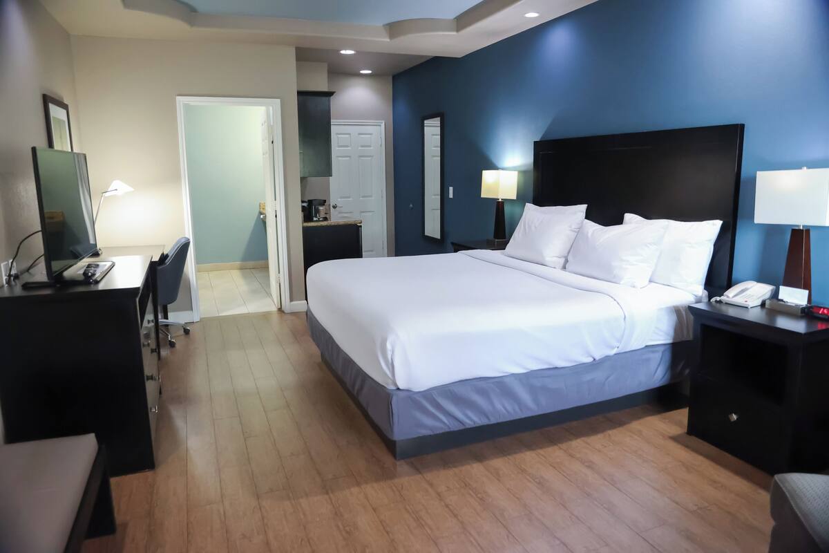 Quarto de hotel com cama, escrivaninha, cadeira e abajures.