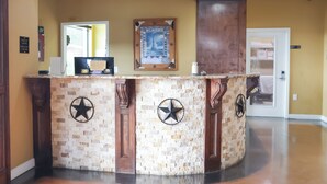 A reception desk with a check-in counter, a framed picture, and a star decoration on the wall. - Black Gold Inn (Yoakum)