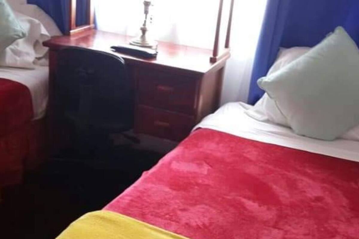 A hotel room with a bed, a desk, and a chair.