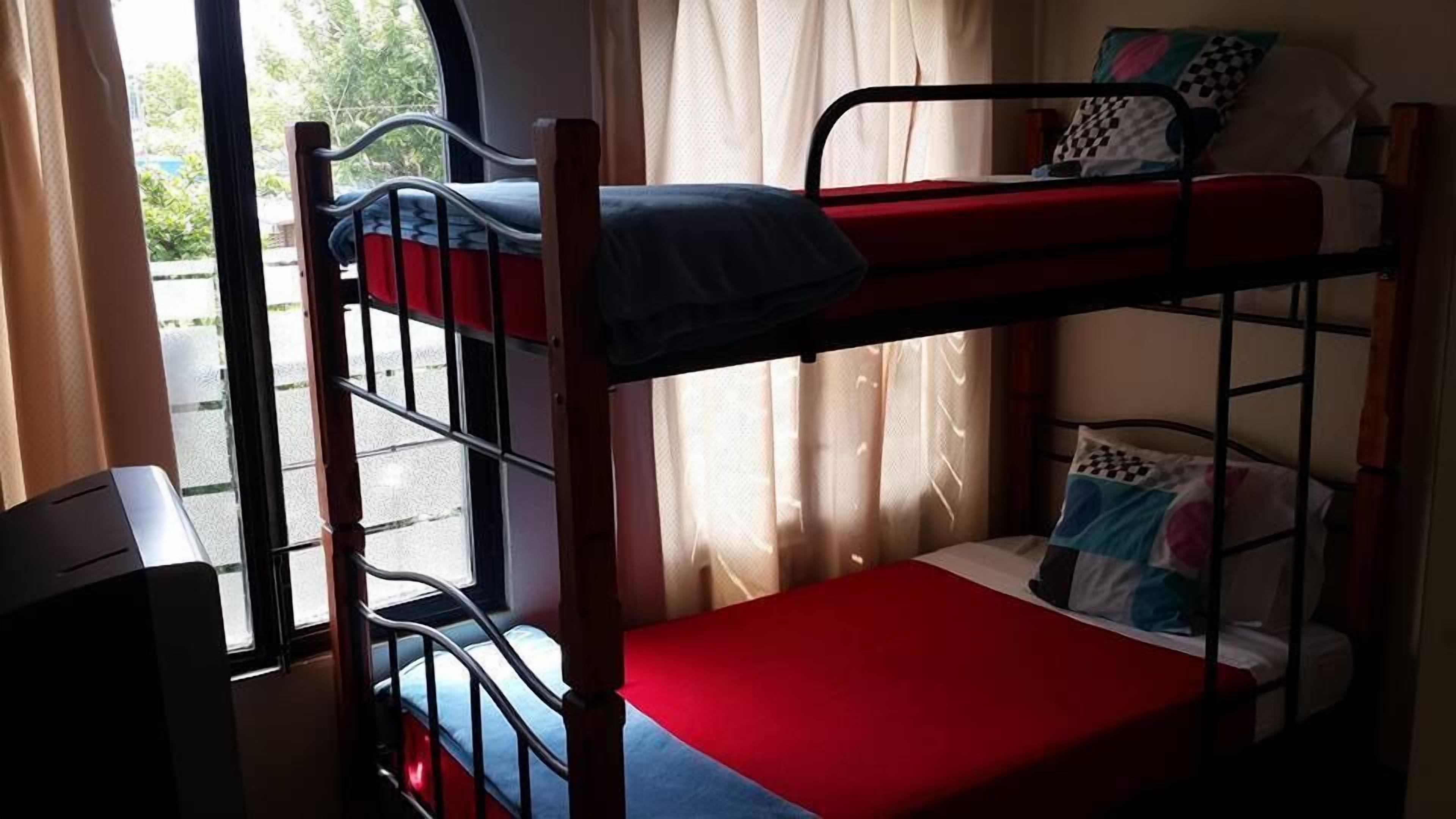 A bunk bed room with a window, curtains, and a desk.