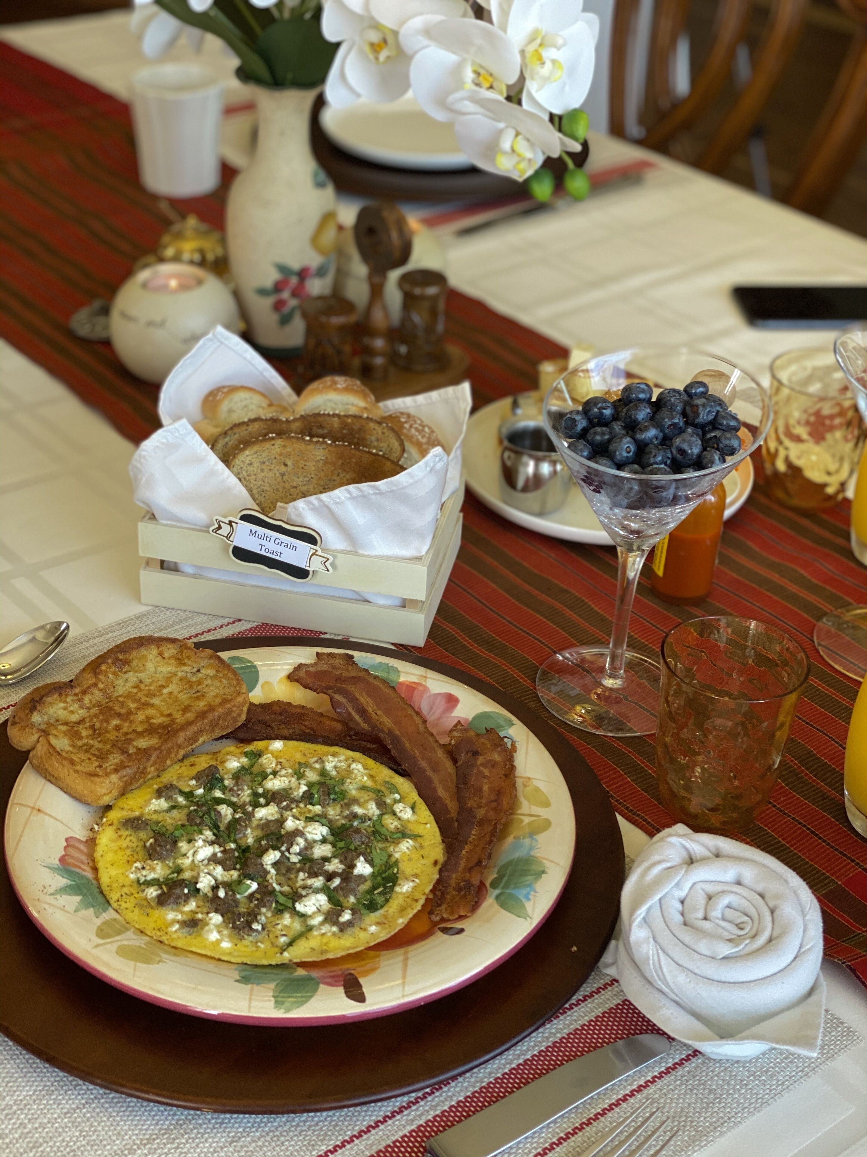 Una mesa de desayuno con tostadas, tocino, huevos y un tazón de arándanos.