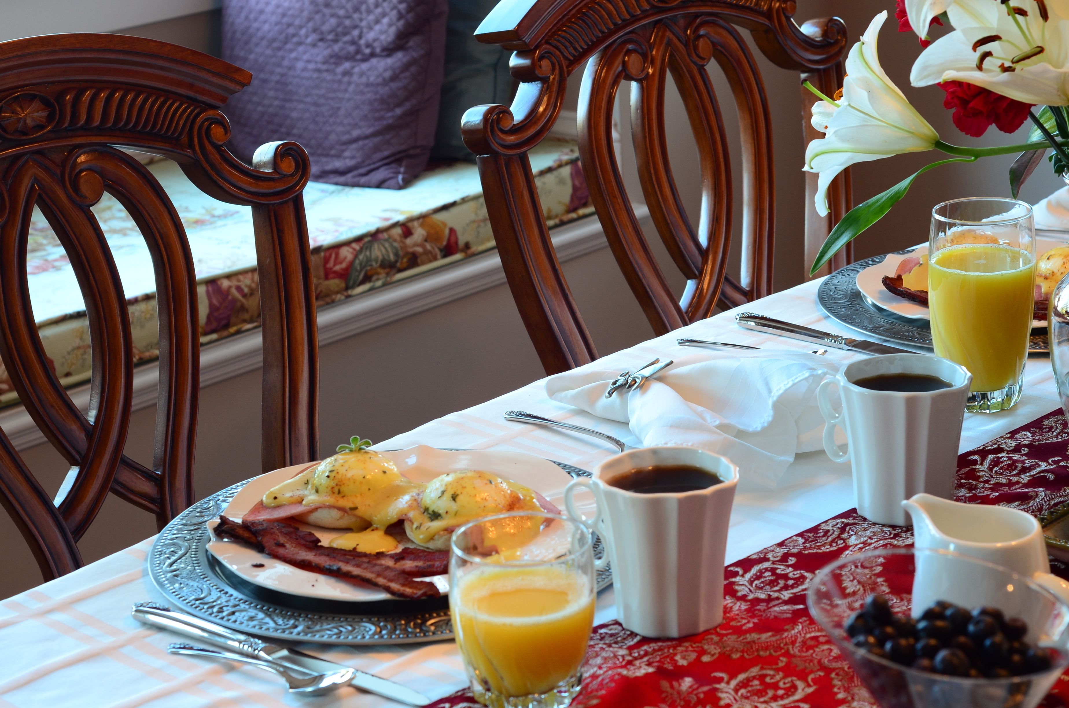Una tavola imbandita per la colazione con uova, pancetta, caffè e succo di frutta.