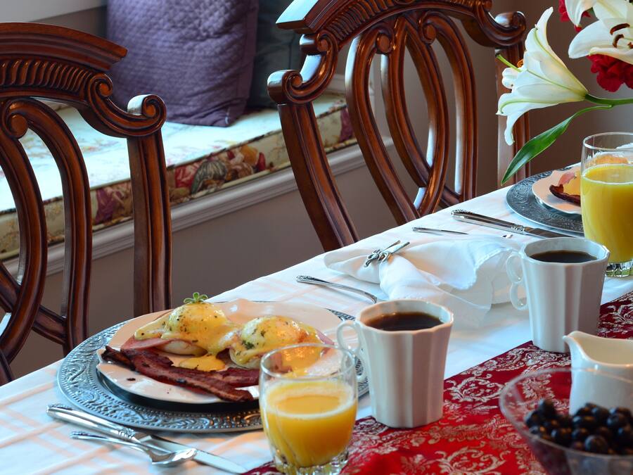 Una tavola imbandita per la colazione con uova, pancetta, caffè e succo di frutta.