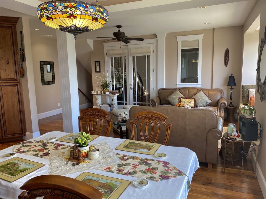 A cozy living room with a dining table set for four, a sofa, and a ceiling fan.