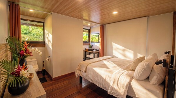 A bedroom with a bed, a bedside table, a window, and a view of the outdoors. - Mei Tai Cacao Lodge (Bijagua)