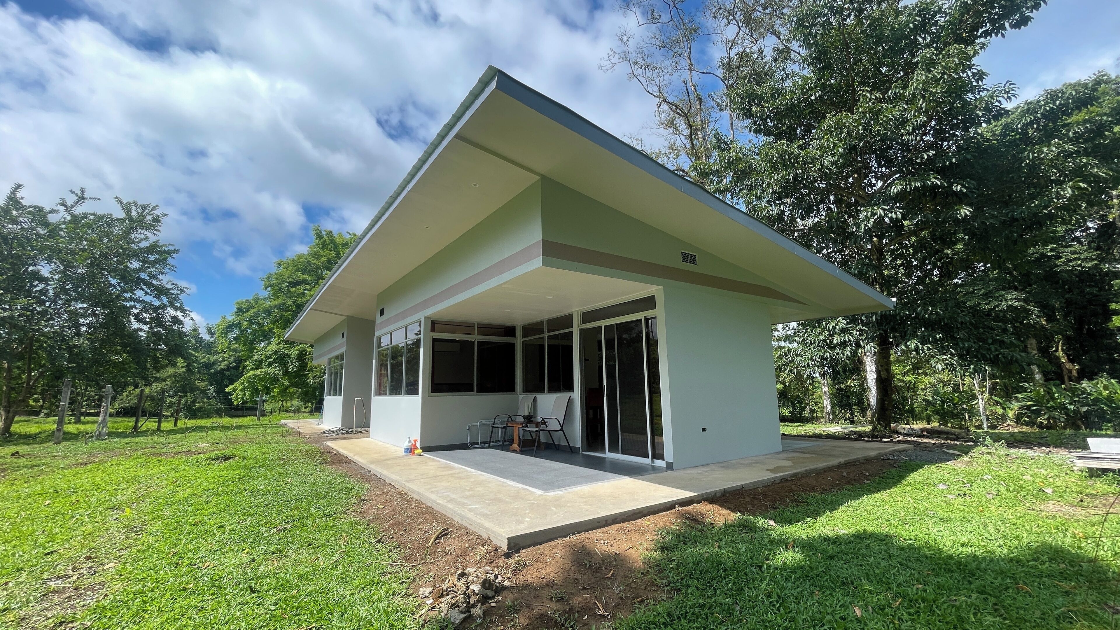 Una casa moderna con techo plano, ventanas amplias y un patio cubierto.