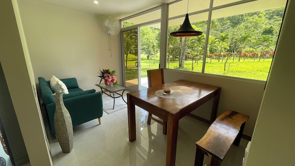 Una sala de estar moderna con un sofá verde, una mesa de centro de vidrio y una mesa de comedor de madera.