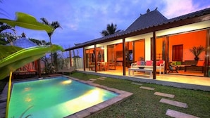 Una casa con piscina, un patio cubierto y un césped bien cuidado.