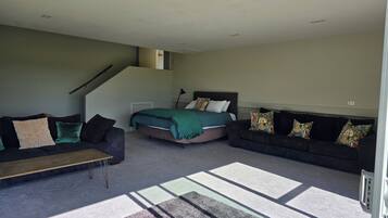A spacious living room with a bed, two sofas, and a staircase.