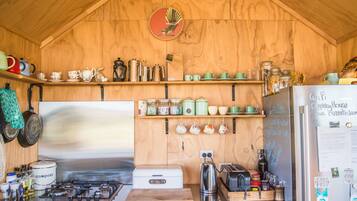 A rustic kitchen with wooden walls, a stainless steel stove, and various kitchen utensils and appliances.