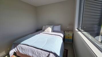 Ein Schlafzimmer mit einem Bett, einem Nachttisch und einem Fenster mit Jalousien.