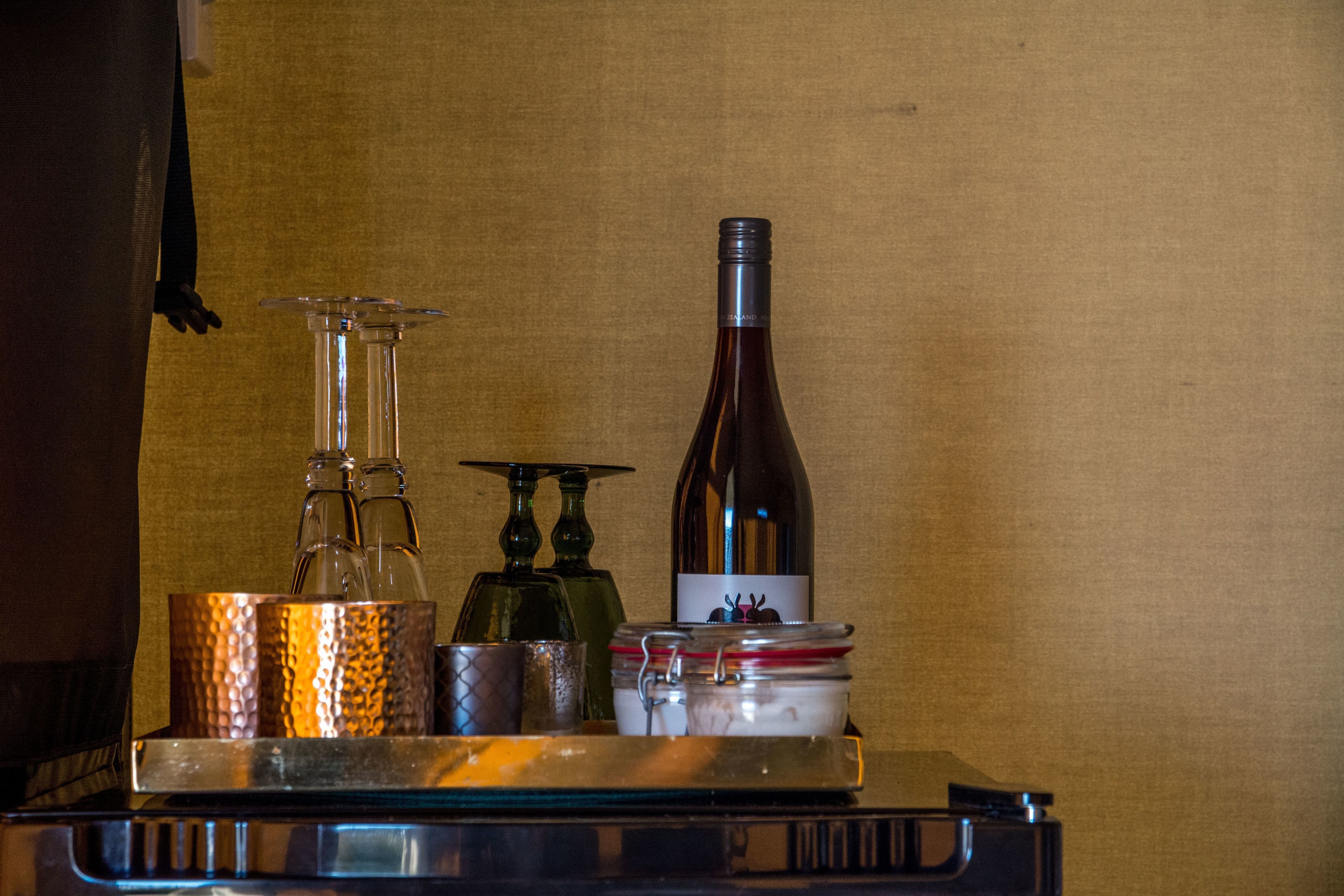 A bar area with a wine bottle, a glass decanter, and a metal tray.