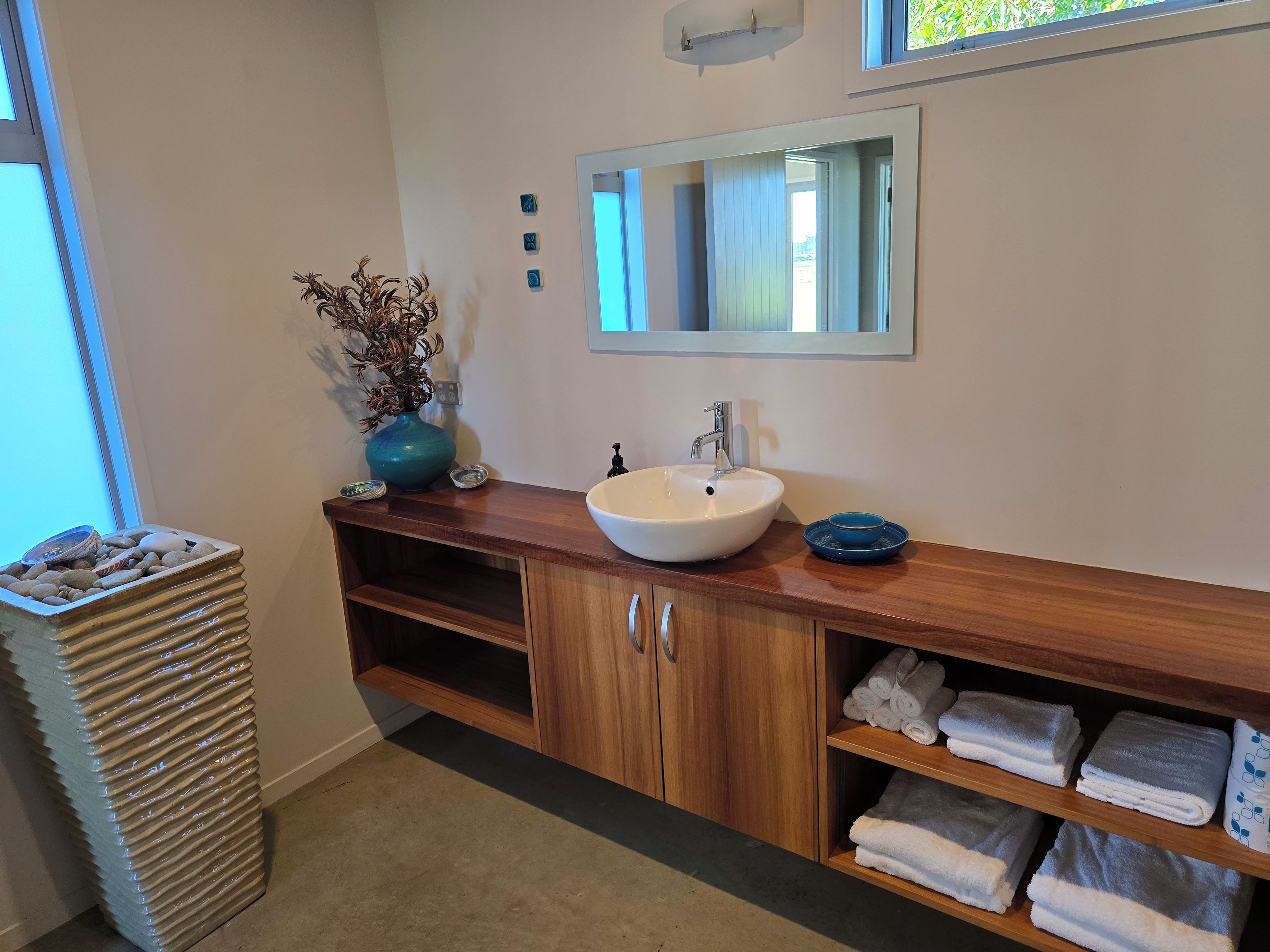 Une salle de bain équipée d’un lavabo, d’un miroir, d’un porte-serviettes et d’une plante.