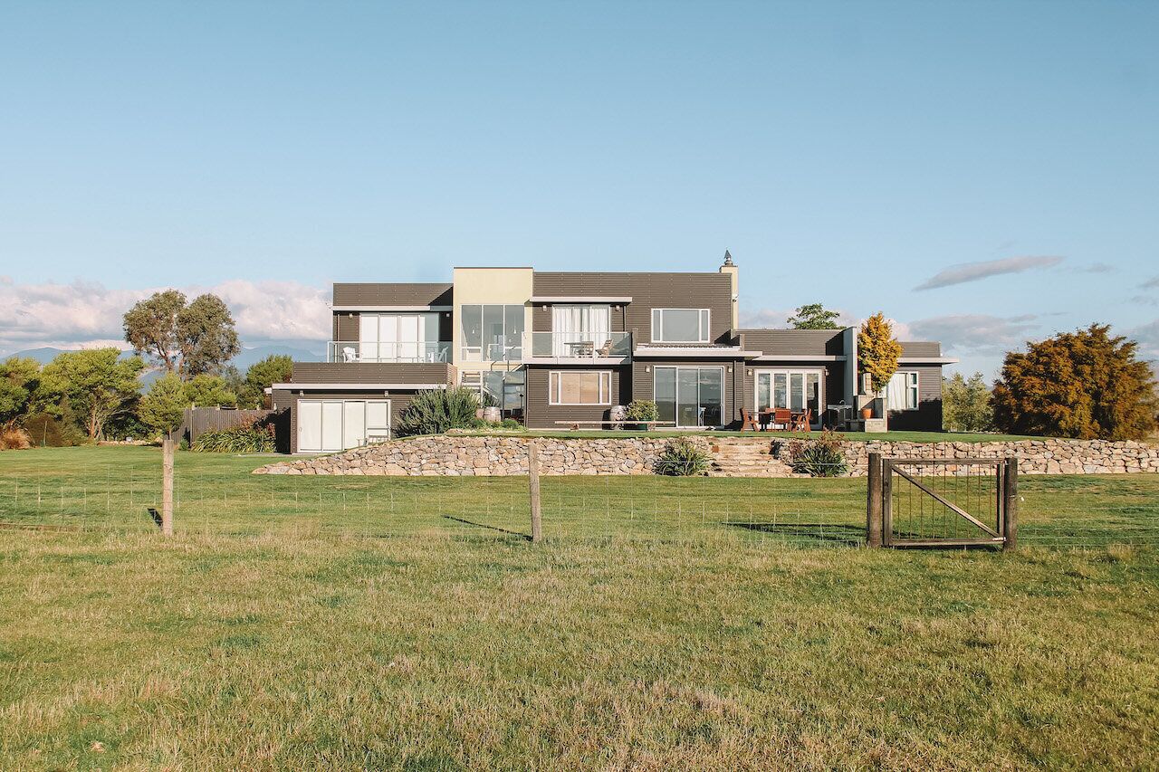A modern two-story house with a stone foundation, large windows, and a well-maintained lawn.