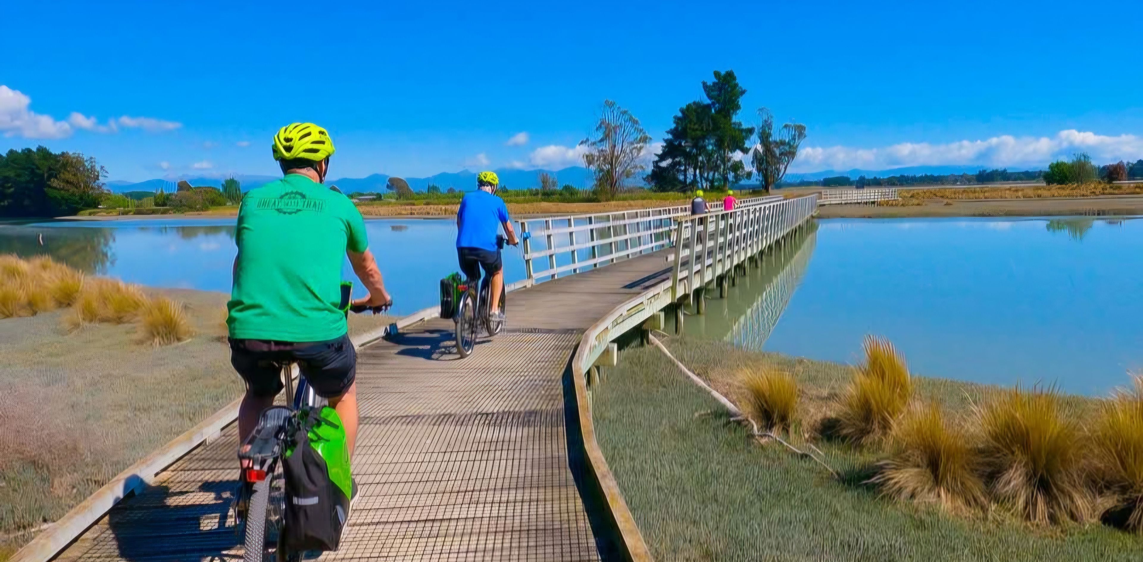 A wooden boardwalk over a body of water with cyclists.
