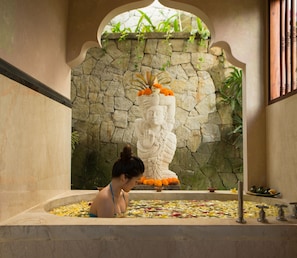 A woman in a bathtub with a statue in the background. - Dwaraka The Royal Villas (Ubud)