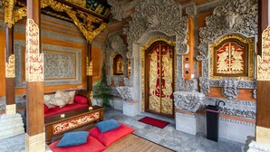 Un interno decorato con una panca in legno, cuscini rossi e intricate sculture.