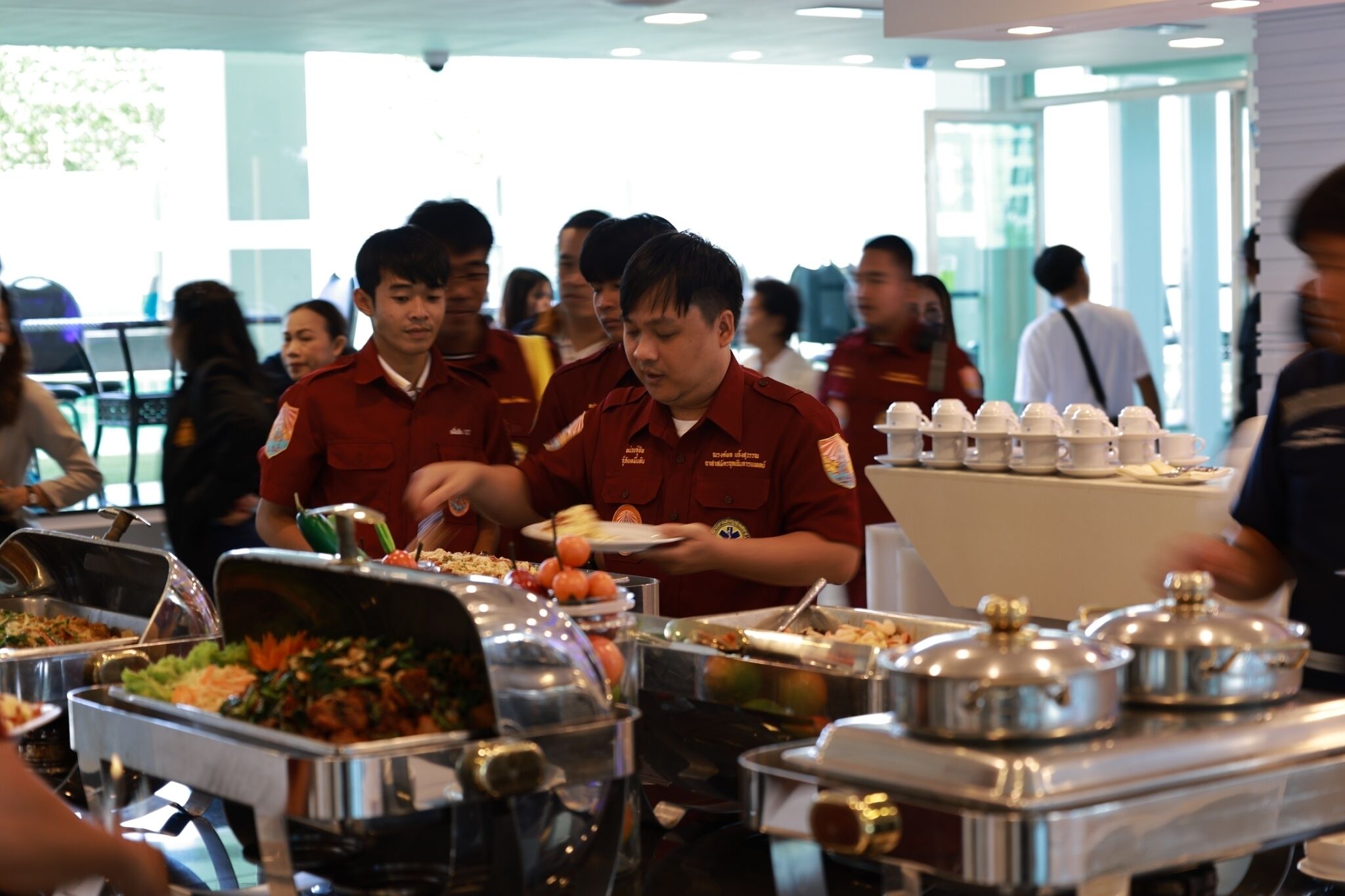 A buffet area with multiple food stations and people serving food.