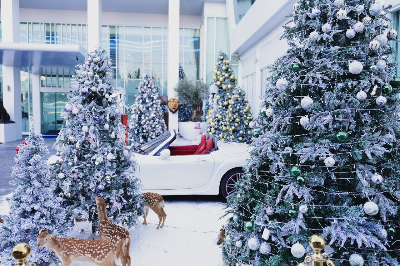 A modern building with multiple Christmas trees decorated with ornaments.