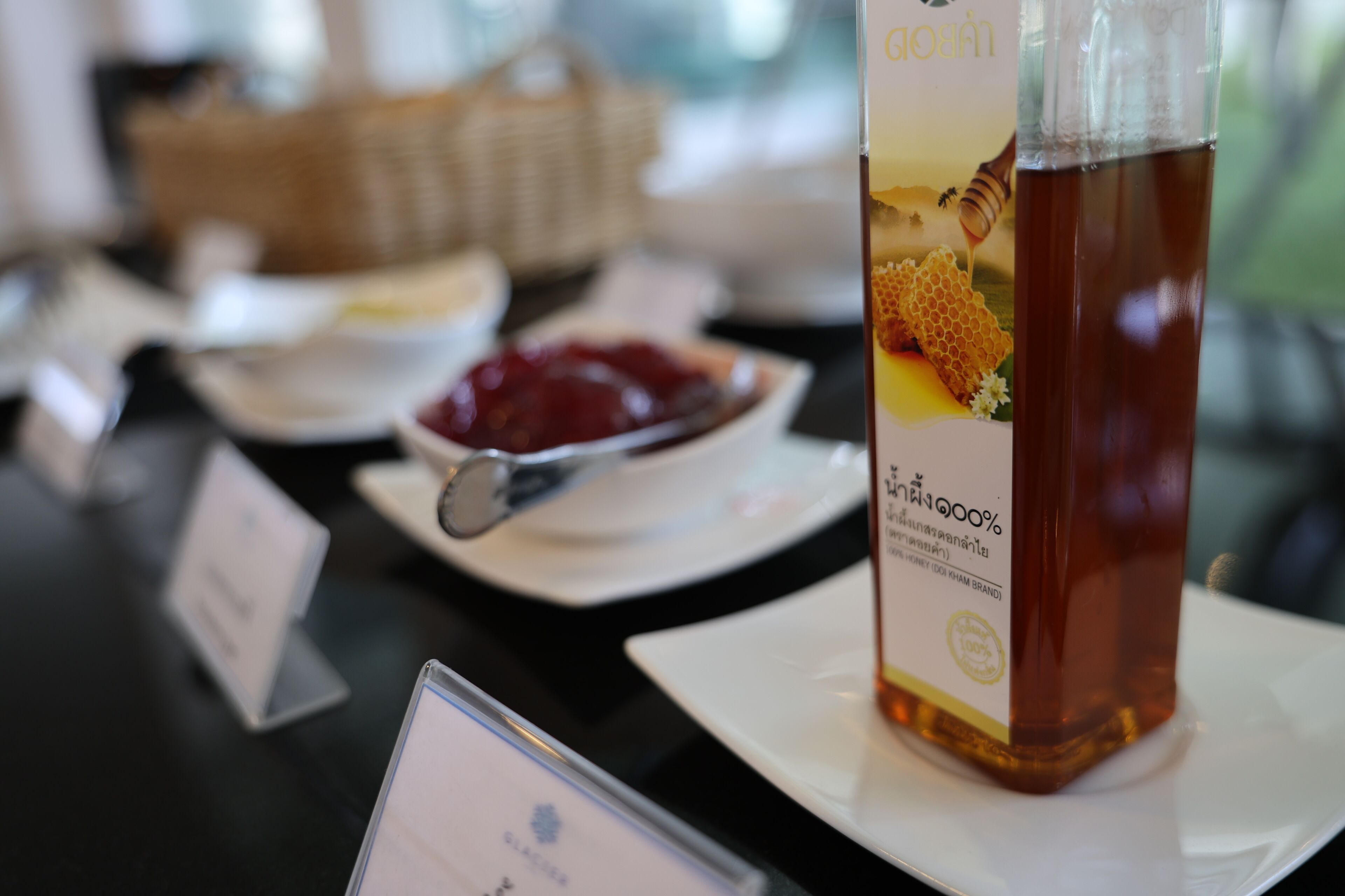 Ein Tisch mit einer Honigflasche, einer Schüssel rote Soße und einem Löffel.
