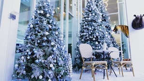 Two decorated Christmas trees in front of a building with large windows. - Glacier Hotel Khon Kaen (Khon Kaen)