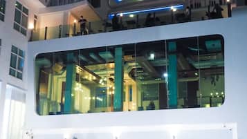 Un edificio moderno con fachada de vidrio, varios pisos y una terraza en la azotea.