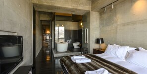 A modern hotel room with a large bed, a flat-screen TV, a bathtub, and a glass-enclosed shower area. - Suiboku (Kutchan)
