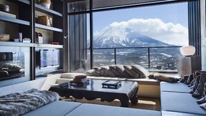 Ein modernes Wohnzimmer mit einem großen Fenster und Blick auf einen schneebedeckten Berg.