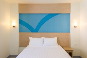A hotel room with a bed, a wooden headboard, and a blue accent wall. - Hop Inn Kanchanaburi (Kanchanaburi)