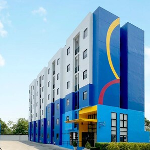 A multi-story hotel building with a modern design, featuring a combination of white and blue exterior walls and a distinctive yellow and blue graphic on the side. - Hop Inn Kanchanaburi (Kanchanaburi)
