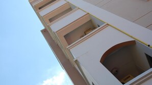 A multi-story building with balconies and a visible door with a sign. - DMa Hotel (Khon Kaen)