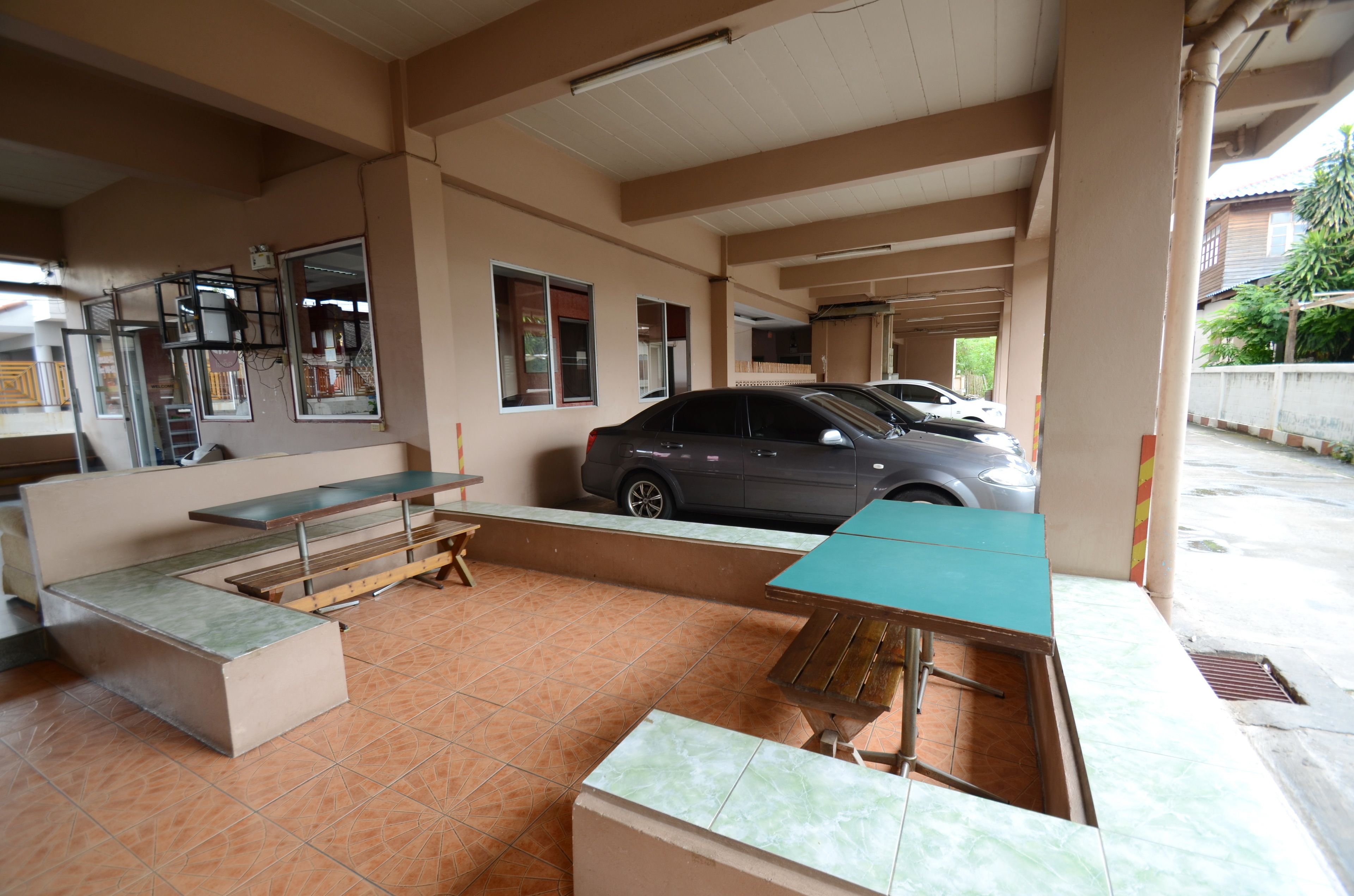 A covered outdoor area with a car parked inside, a bench, and a table.