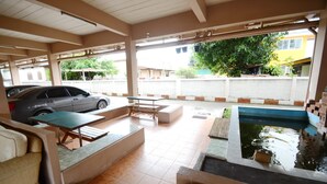 A covered outdoor area with a car parked nearby, a small pool, and seating arrangements. - DMa Hotel (Khon Kaen)