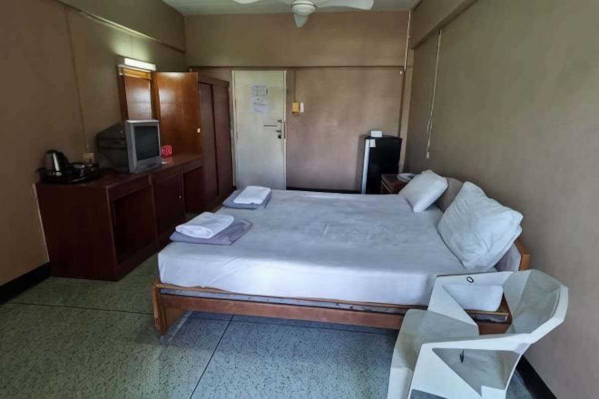 A hotel room with a bed, a desk with a television, a chair, and a wardrobe.