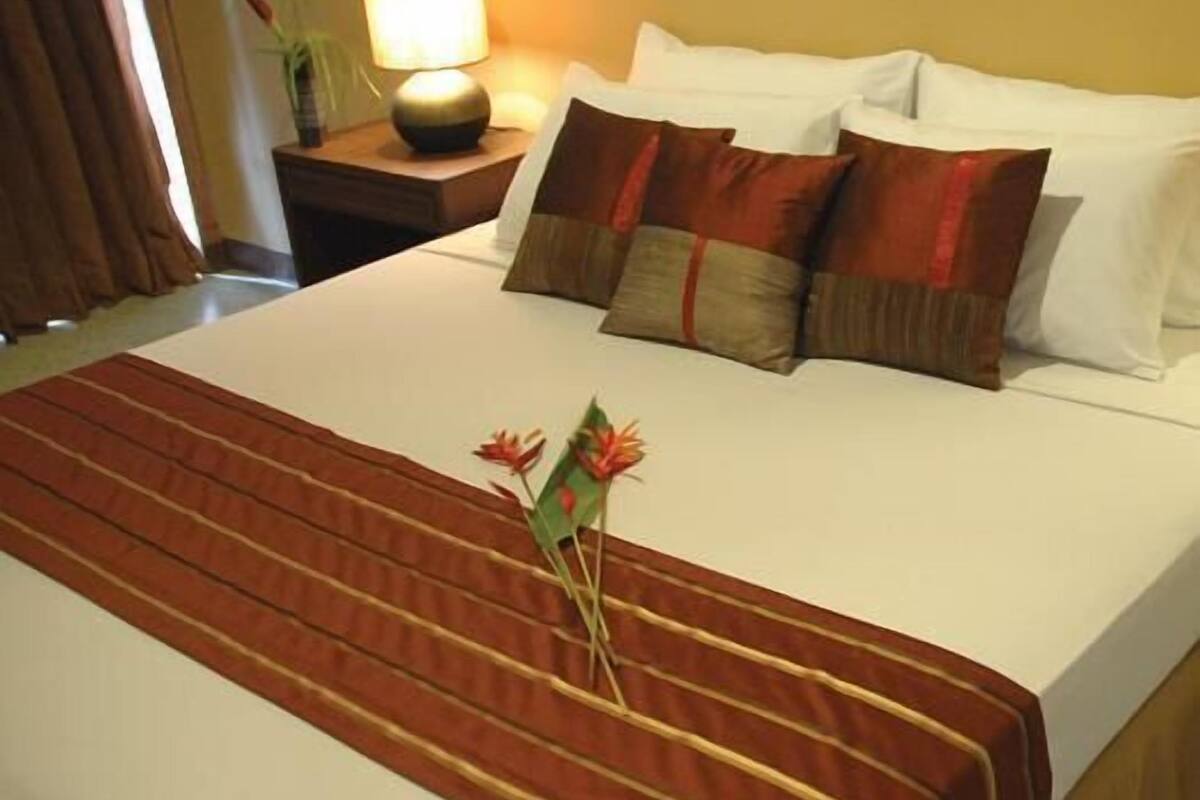 Une chambre d’hôtel avec un grand lit, une table de chevet avec une lampe et une fenêtre avec des rideaux.