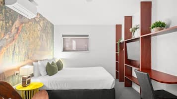 A modern hotel room with a bed, a desk, a chair, a TV, and a window.