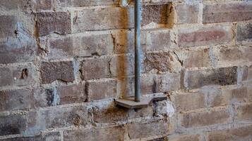 A brick wall with a metal pole and a small shelf.