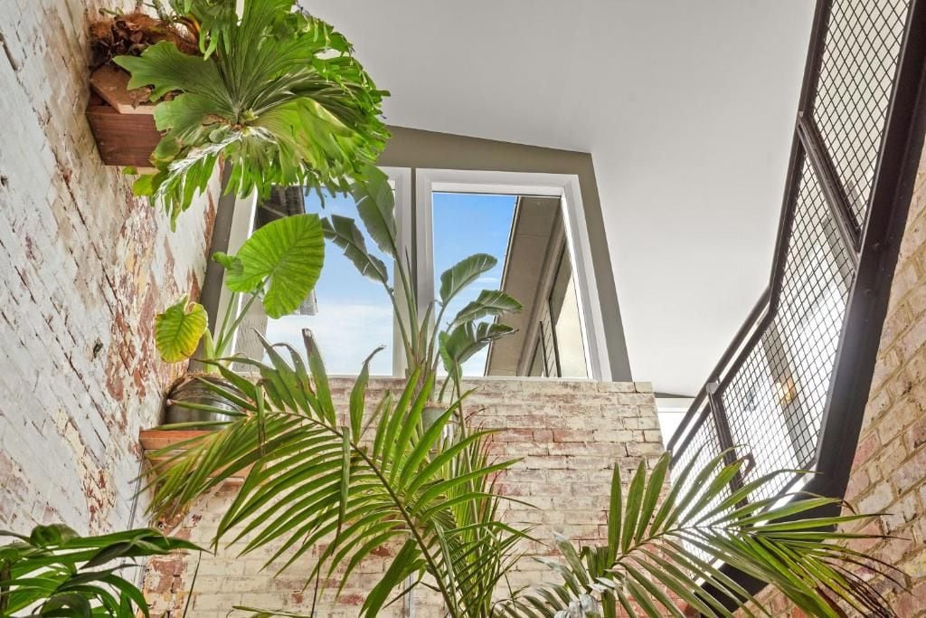 A room with a brick wall, a window, and potted plants.