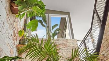 A room with a brick wall, a window, and potted plants.