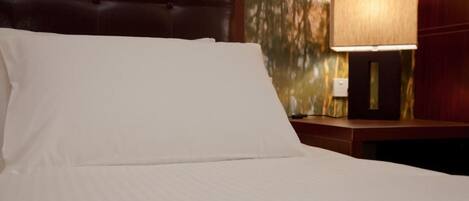 A hotel room with a bed, a nightstand, and a lamp.