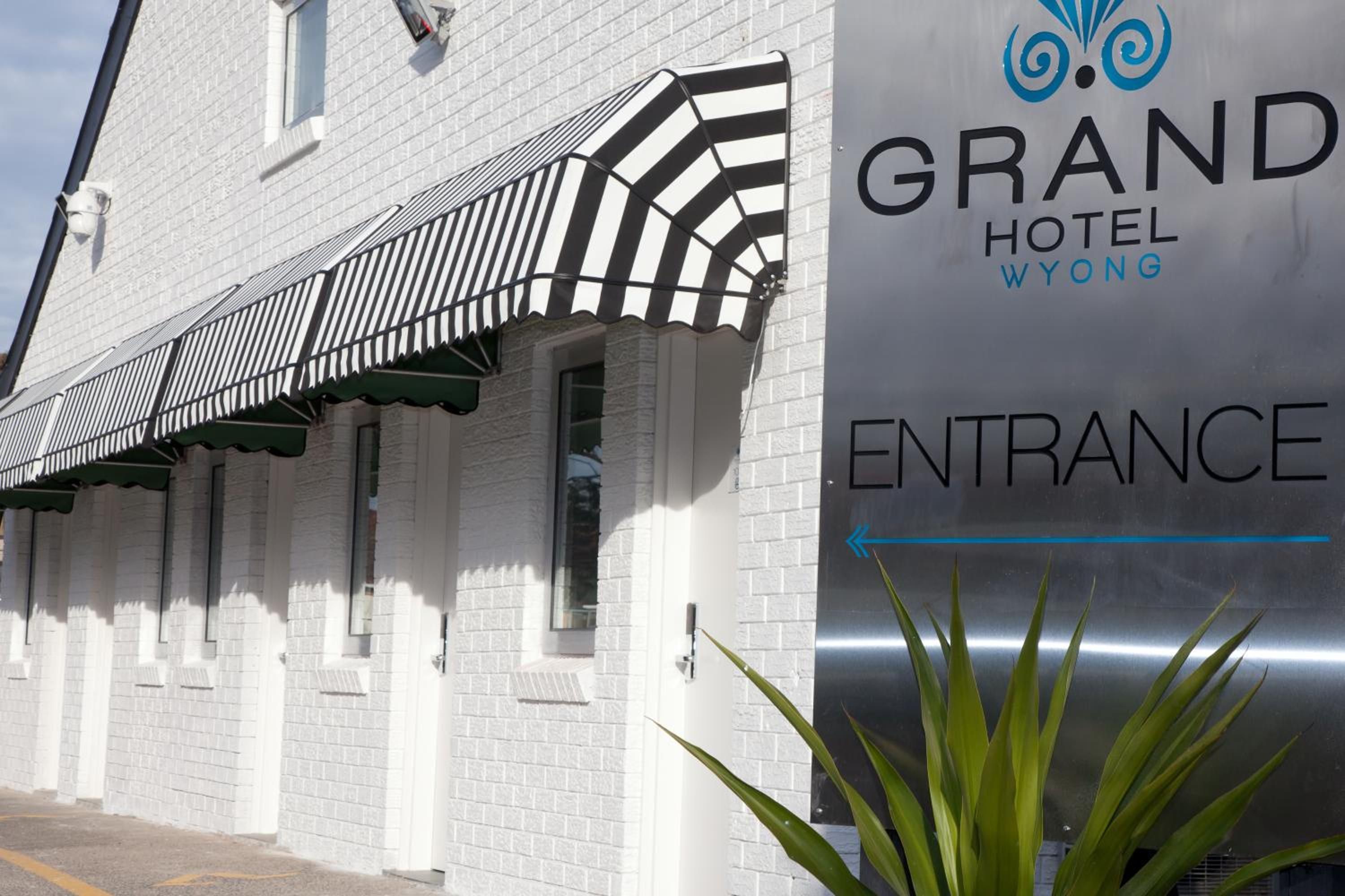 The exterior of the Grand Hotel Wyong with a striped awning and an entrance sign.