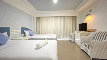 A hotel room with two beds, a TV, a desk, and a chair.