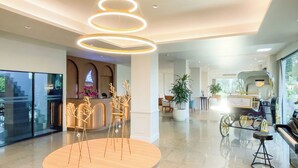 A modern hotel lobby with a reception desk, a piano, and a rickshaw display. - Rua Rasada Express (Trang)