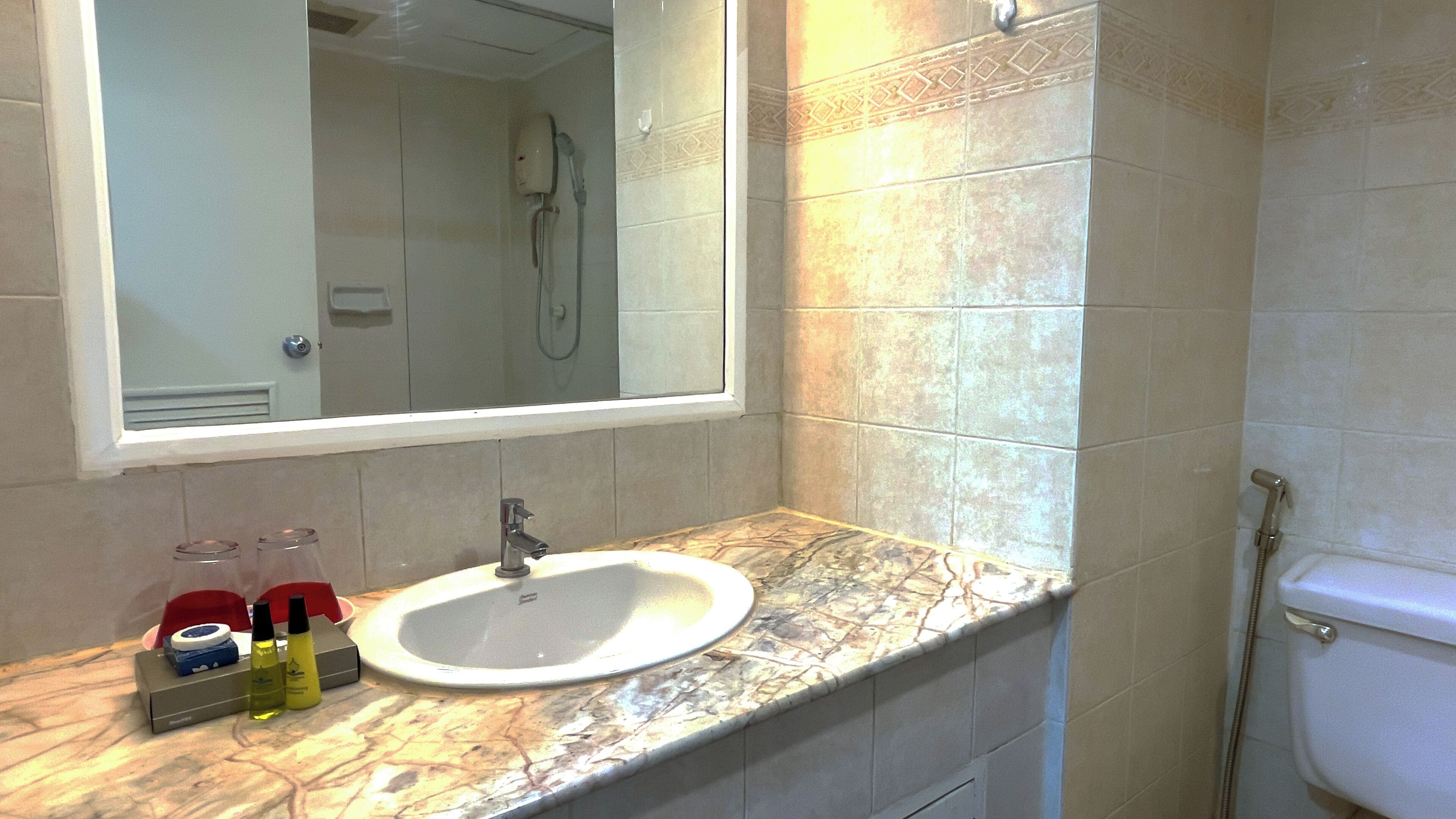 Un baño con lavabo de mármol, un espejo y una ducha.